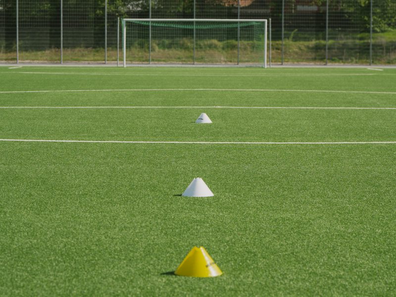 Three cones in a line leading to a goal on an empty pitch